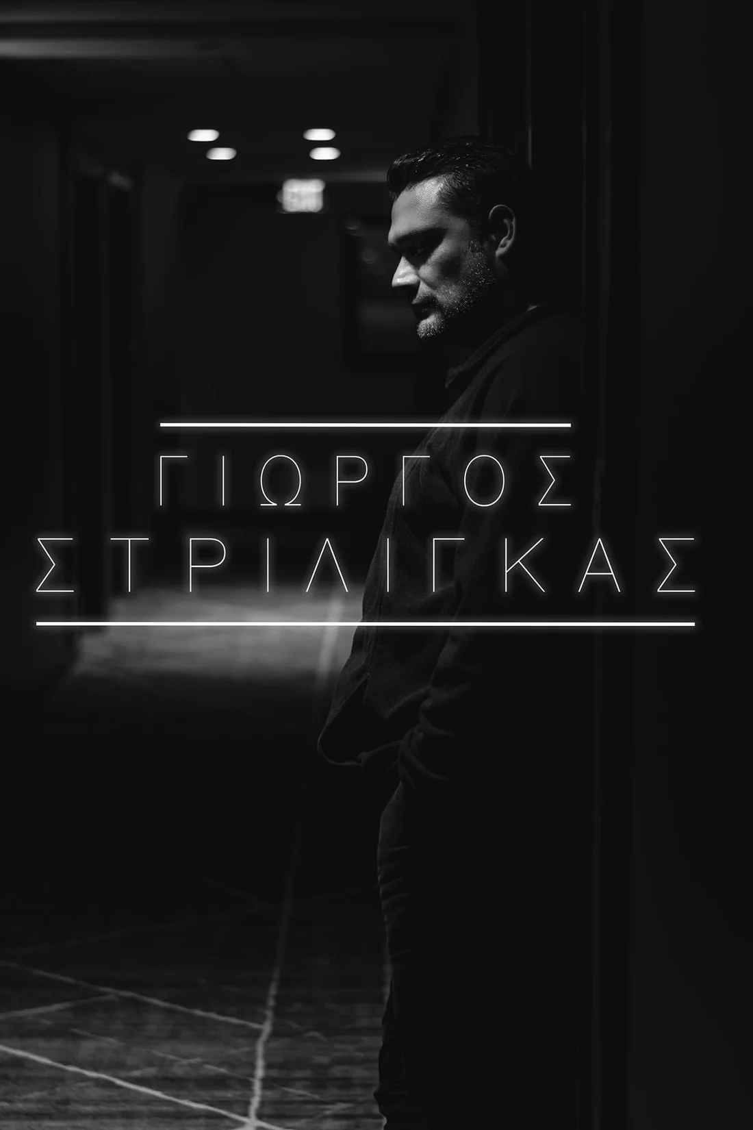 Black-and-white portrait of George Strilingas standing in a dim hallway, with his name in Greek lettering